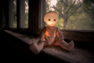 Child's doll glowing in the dust of a chernobyl window